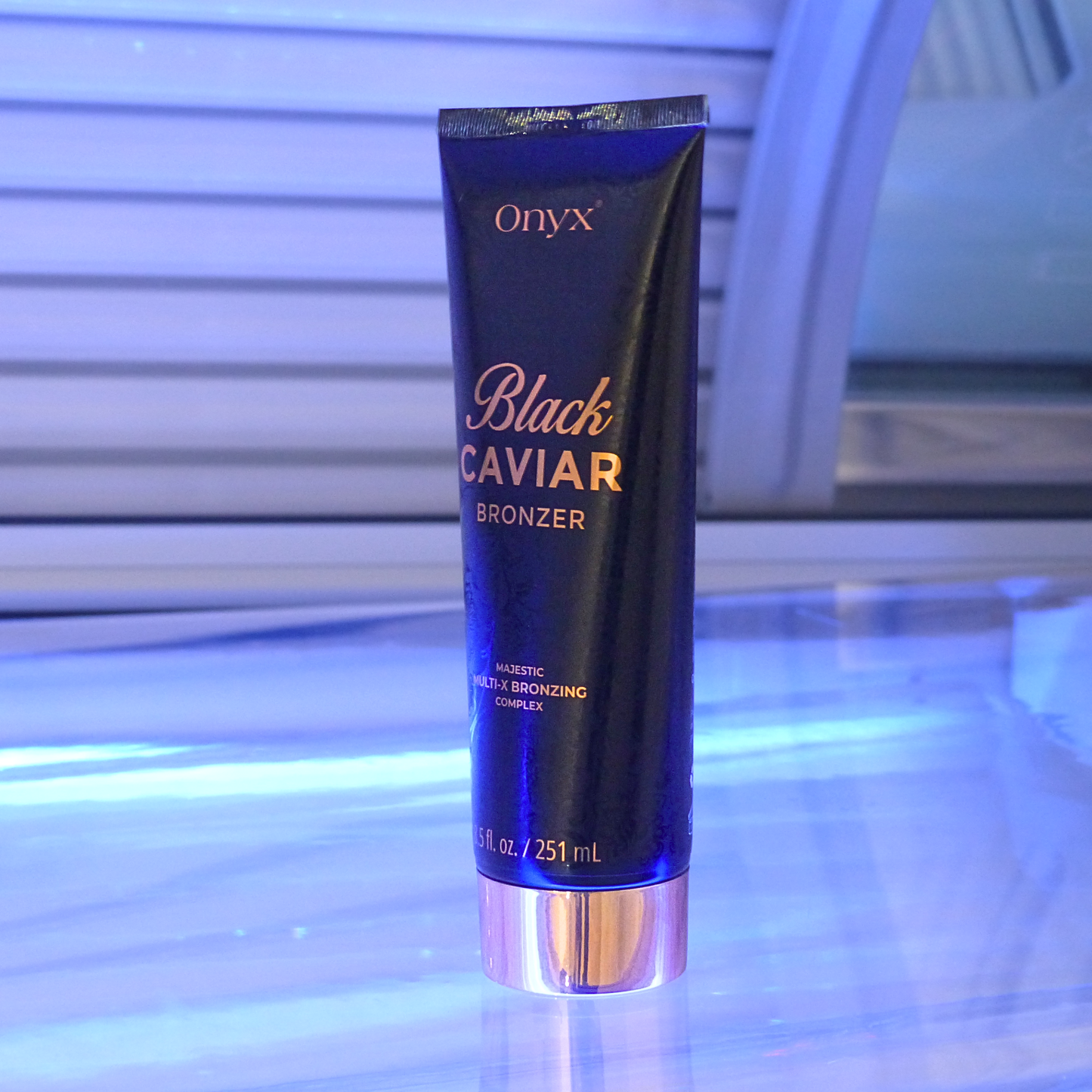 Onyx Black Caviar Bronzer ustawiony w solarium w niebieskim świetle; luksusowy bronzer do opalania w solarium z efektem gładkiej, nawilżonej skóry