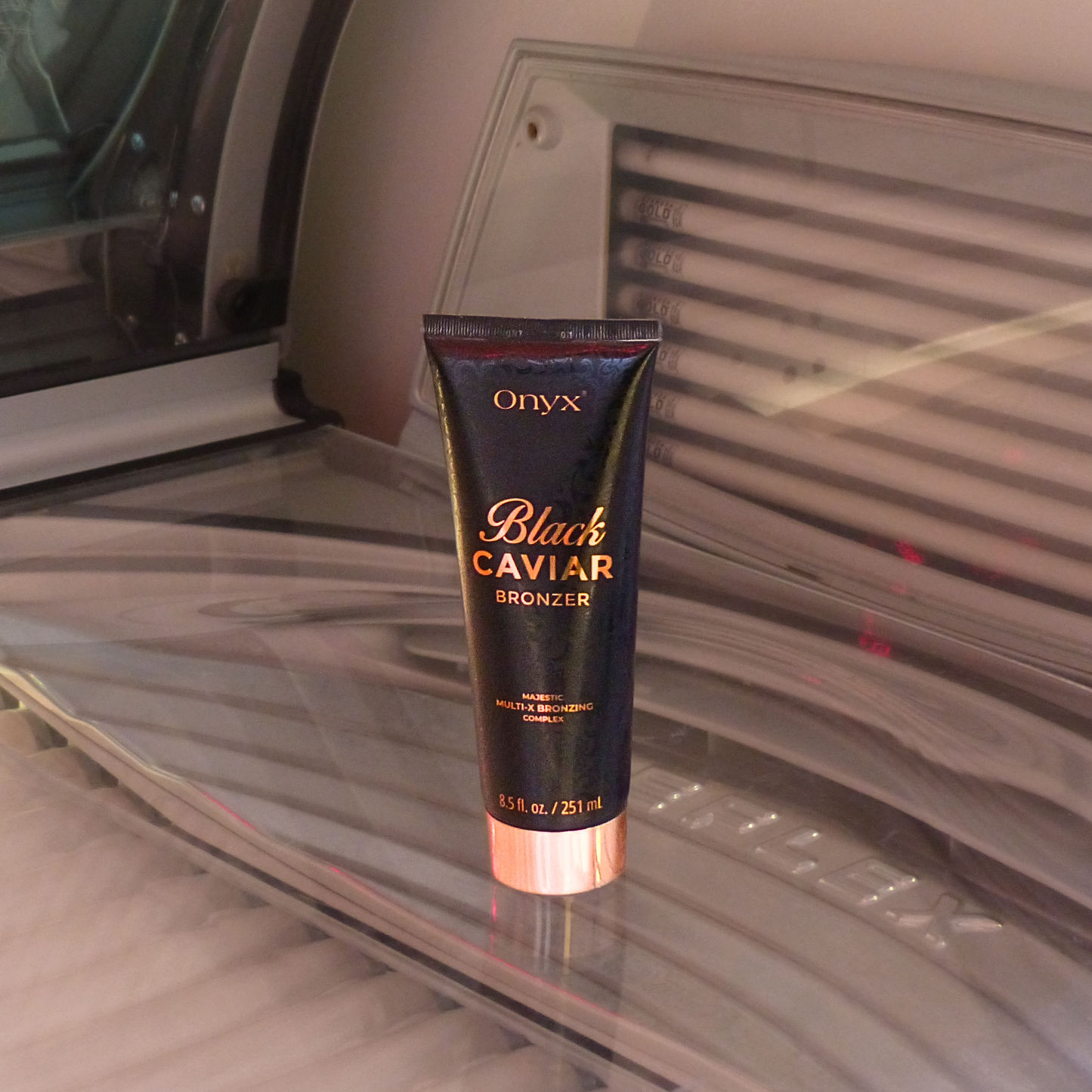 Onyx Black Caviar Bronzer ustawiony w solarium na leżance; bronzer do opalania w solarium z kompleksem Multi-X Bronzing dla ciemnej i równomiernej opalenizny