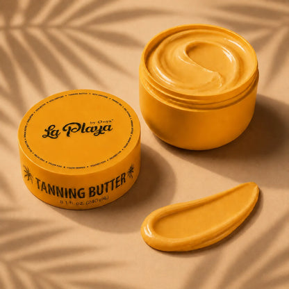 A jar of La Playa by Chava Tanning Butter shown open with a swirl of golden-yellow cream inside, alongside a dollop of the product on a beige surface with soft leaf shadows.