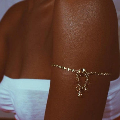 Zbliżenie na opaloną rękę kobiety ozdobioną złotą bransoletką, skóra ma wyraźny połysk i równy odcień po użyciu balsamu rozświetlającego Onyx La Playa