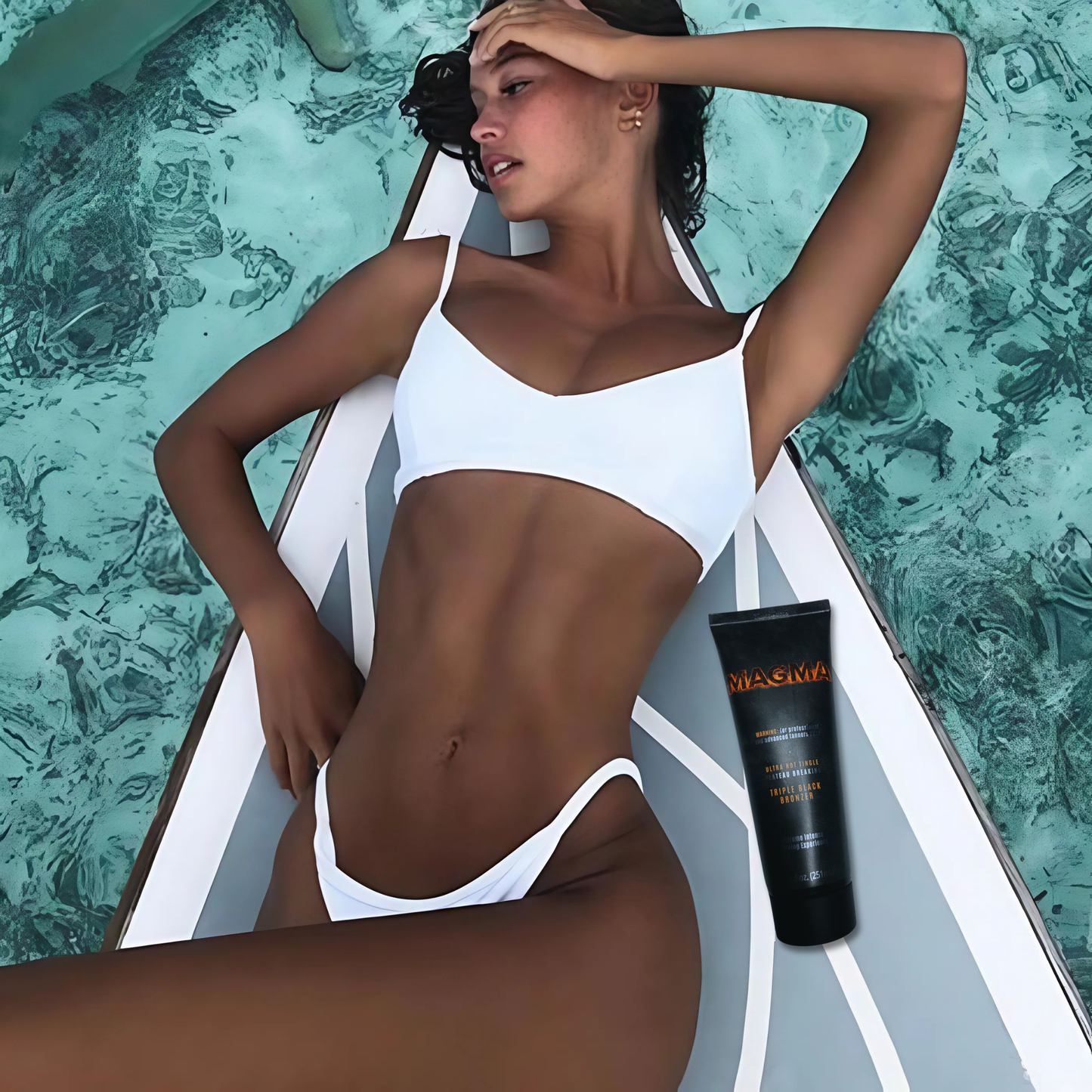 Kobieta w białym bikini opala się przy wodzie z bronzerem Onyx Magma. Efekt tingle zapewnia wyjątkowo głęboki ton skóry.