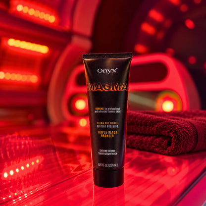 Onyx Magma Tingle stojący wewnątrz czerwono oświetlonego łóżka solaryjnego obok złożonych ręczników. Produkt pokazany w typowym otoczeniu jego zastosowania.