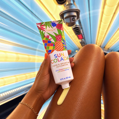 Onyx Sun Colada wyciskany bezpośrednio na nogę wewnątrz łóżka solaryjnego. Zdjęcie pokazuje żółtawą konsystencję balsamu przed rozprowadzeniem na skórze.